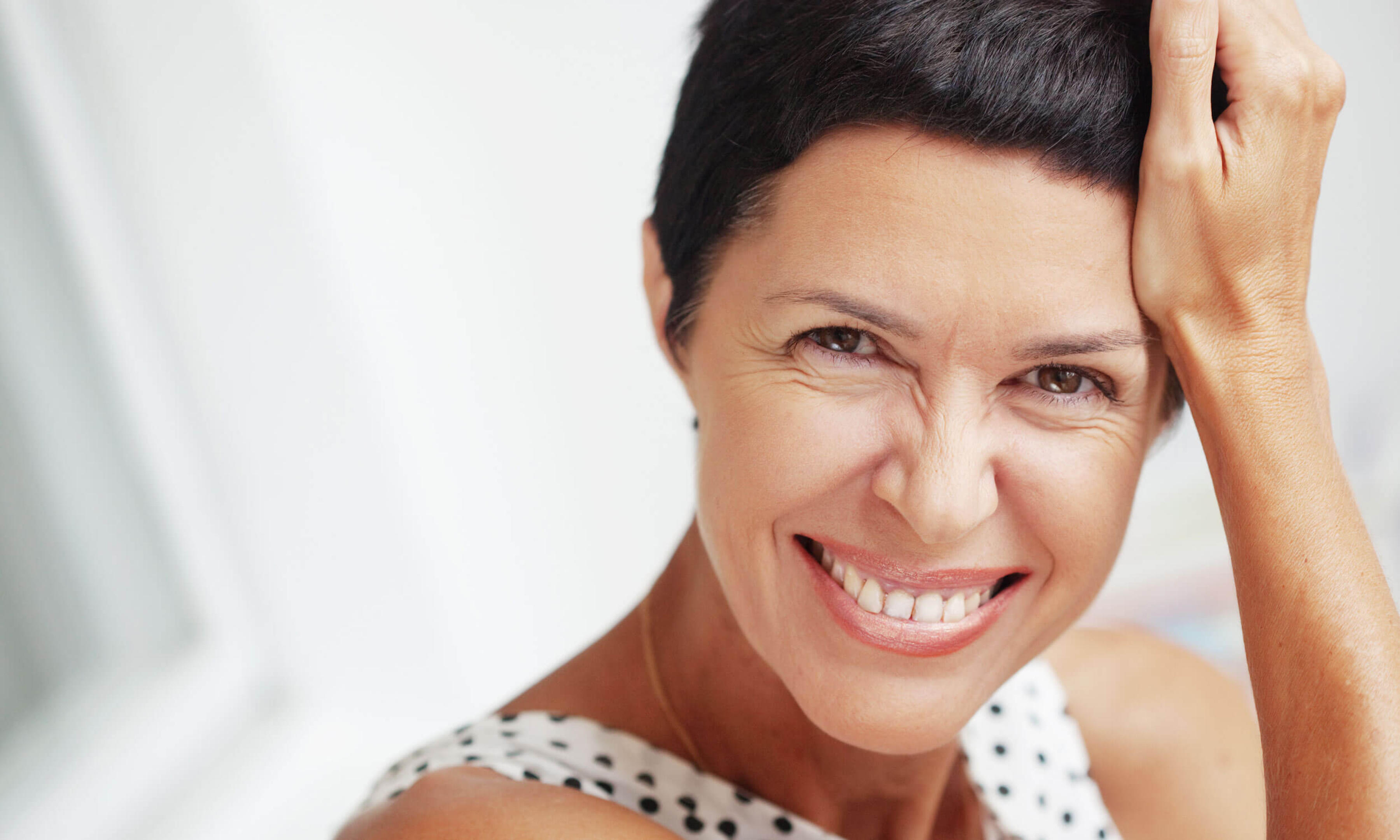 A woman smiling an leaning on her right hand