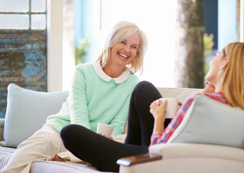 Two women on a white couch laughing