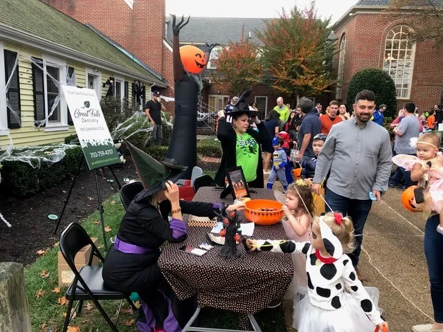 Team members greet kids at a halloween event